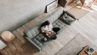 eine Frau sitzt auf einem Sofa und benutzt einen Laptop