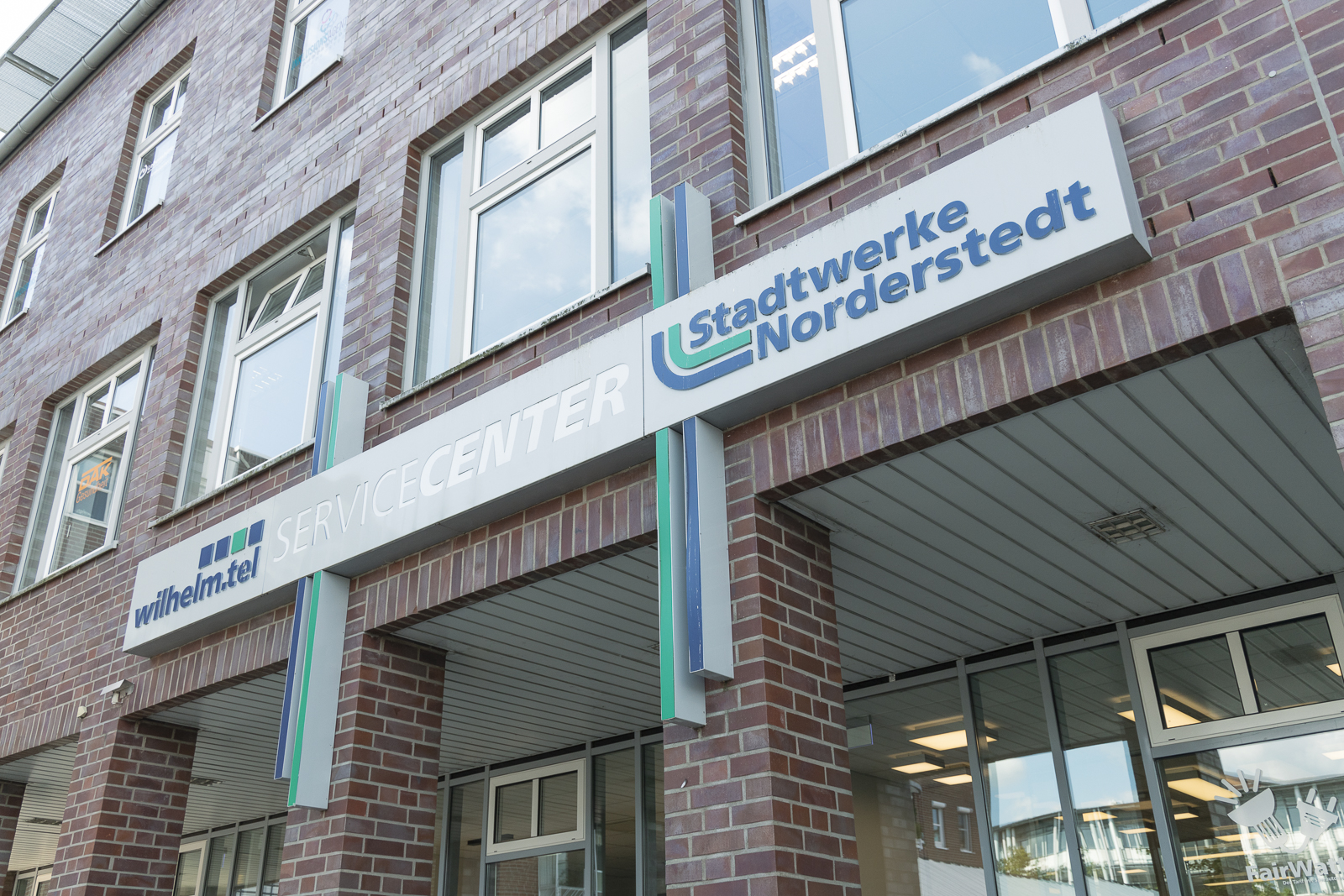 ein Schild mit Logos von wilhelm.tel und Stadtwerke Norderstedt über dem Eingangsbereich des ServiceCenters